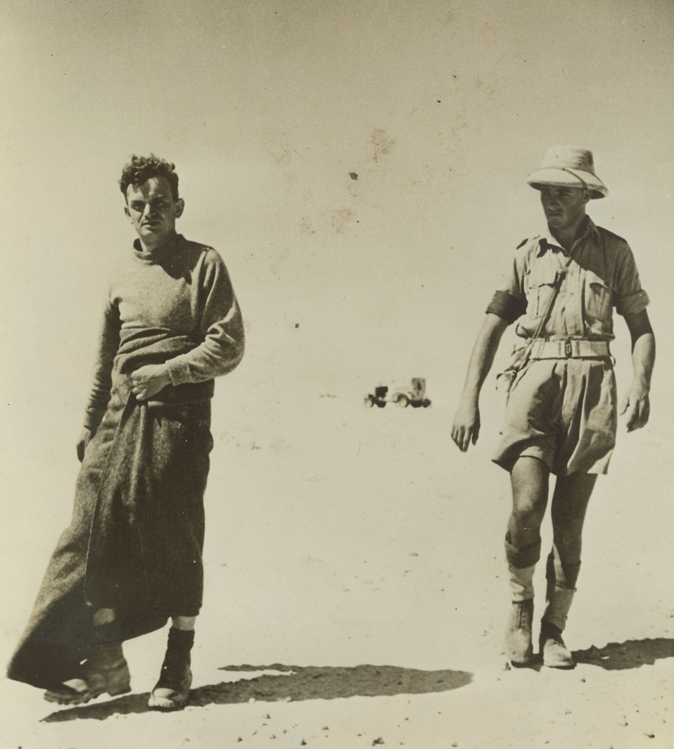 Desert Mornings Are Cold, 8/31/1942. Egyptian Desert – This Italian prisoner, under guard of a New Zealand military policeman, was captured before he could get into his pants during a dawn attack in the Egyptian desert.  He wears the blanket as much for comfort as modesty, since the early morning air is cold in the desert. Credit line (ACME);