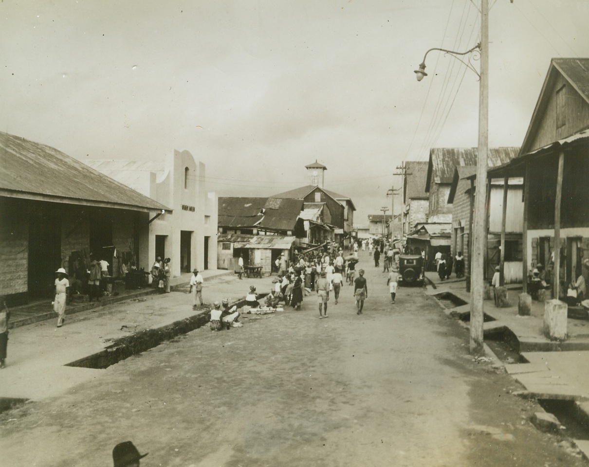 Shopping Center of Liberia, 8/27/1942. Monrovia, Liberia—View of Water Street, on the waterfront on Monrovia, capital of Liberia. Here are located most of the trading concerns in the city. At the left are two European trading shops; further along, under the broken down roof, is a native sea-fish market. The clock tower in the center background surmounts the Government Customs Building. The street has open sewers, but is electrically lighted at night, the power coming from a government-operated plant. Editors: These photos of scenes in Liberia are sent to you for use with future wire stories, please file them for reference. Credit: Firestone Company—from ACME.;