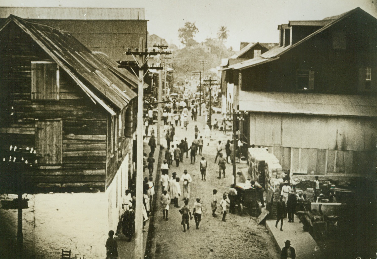 Liberian Street Scene, 8/27/1942. Monrovia, Liberia—American cultivation of rubber began on a large scale in Liberia, on the west coast of Africa, when the Firestone organization began its planting on two 50,000 acre plantations. Since then, American institutions—chain stores, electric lights, autos, movies, radio, and paved streets—have become familiar sights in this 100-year-old Negro Republic. Here is a typical street scene in the native quarter of Monrovia, the capital of Liberia, which was named after President Monroe. Editors: these photos of scenes in Liberia are sent to you for use with future wire stories. Please file them for reference. Credit: ACME.;