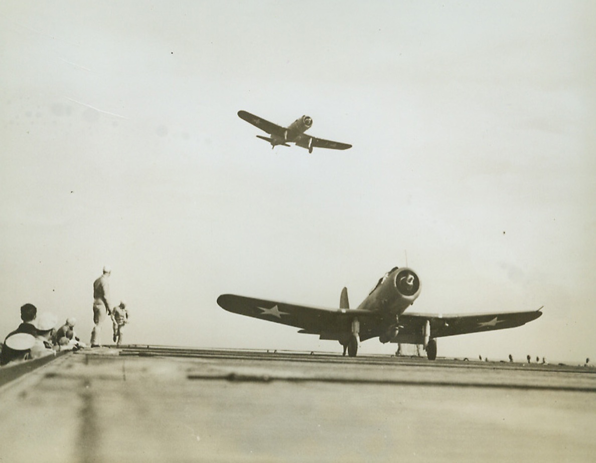 Happy Landings, 8/4/1942. Washington—The remarkable thing about this familiar scene is that the aircraft carrier on which these dive-bombers are landing and taking off is a former merchant ship converted by the skill of American shipyard workers into the aircraft carrier Charger. Uncle Sam is making use of every facility for hurling planes against enemy sea forces.Credit: Official U.S. Navy photo from ACME.;