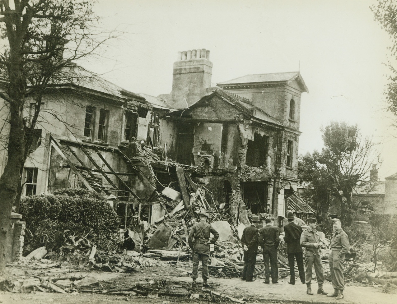 Nazi Funeral Pyre in Britain, 8/13/1943. England – One of two houses damaged when a German Heinkel III crashed after its motors had stopped suddenly, its bomb load exploding and setting the houses afire, at a South Coast town in England. Four people sleeping in the houses were treated for burns. Note hole in roof of second house, (right background in photo). (Passed by censors) Credit: ACME;