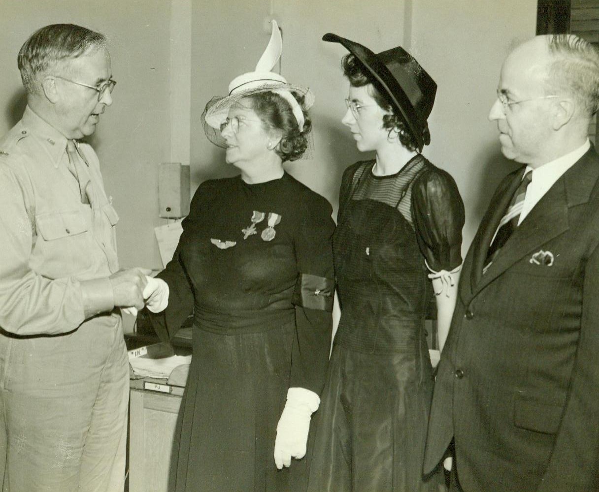 Recieves Son's Posthumous Awards, 8/13/1943. New York, N.Y.—Mrs. Mary C. Church, of 66 Deleware Avenue, Dumont, N.J., mother of the late 1st Lieut. Russel M. Church, Jr., 17th pursuit Squadron, U.S. Army Air Forces, received the Distinguished Service Cross and Soldier’s Medal, posthumously awarded to her son who was killed in action in the Philippines December 16, 1941. Here, in ceremonies in the office of Col. Thomas L. Crystal, post commander, Fort Jay, Governors Island, are, (Left to Right): Col. Crystal, who presented the medals; Mrs. Church; Miss Mary Church, the hero’s sister; and Russel M. Church, Sr., his Father. Mrs. Church wears her son’s wings and the two medals, (The D.S.C. on left and Soldiers medal, right).  8/13/42 (ACME);