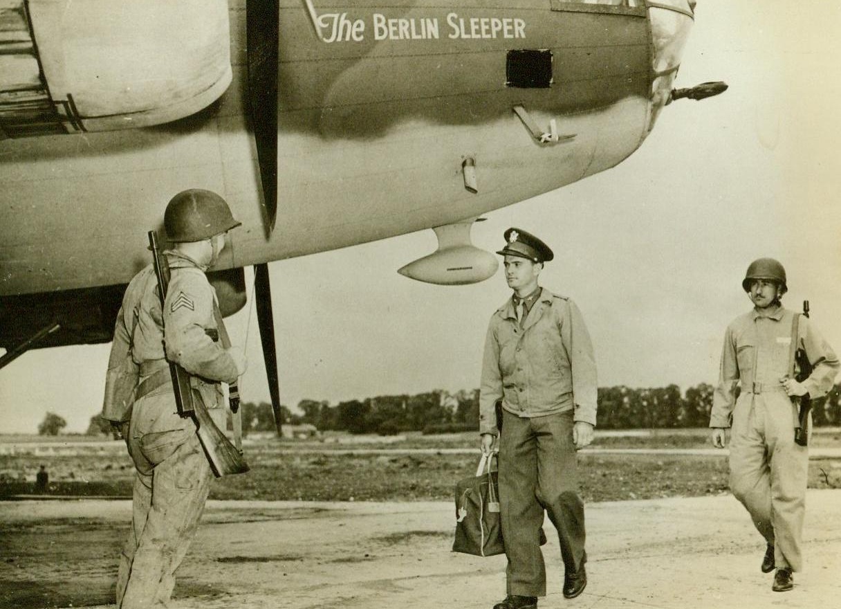 Ready To Deliver Sleeping Powder To Nazis, 8/5/1942. Somewhere in the British Isles – In many parts of the British Isles, U.S. Air Force flying fortresses are waiting for the “zero hour,” waiting to deliver “block-buster” bombs to Berlin – And anywhere else the Nazis may be gathered. Here, Lt. Edward B. Weathers, of Ocala, Fla., walks up to his bomber, which is appropriately named, “The Berlin Sleeper.” He is accompanied by soldiers carrying sub-machine guns, for he carries the valuable and secret American bombsight.  8/5/42 (ACME);