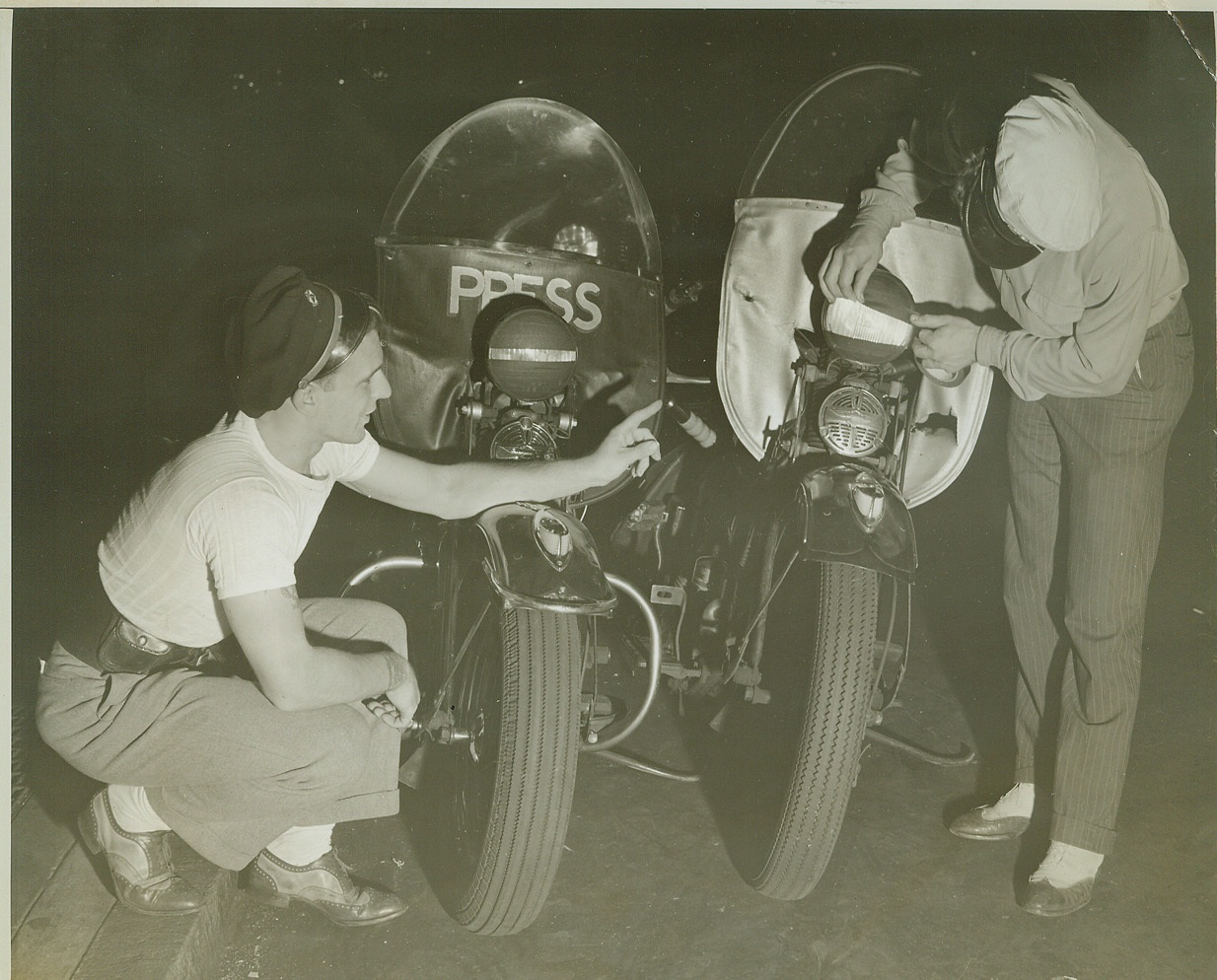 Motorcycle Riders Join Dimout, 8/4/1942. NEW YORK, N.Y. – Two press motorcycle riders, who must be prepared to ride through blackouts, Jack Schultz, (left), and Frank Mote, both of Acme Newspictures, Inc., tape up their headlights to conform to the ruling that auto lights be dimmed out to the intensity of parking lights, beginning August 4th. For the first 10 days, violators will only be given warnings. After that, magistrates will be empowered to impose penalties up to $50 or 30 days, or both. Credit: (ACME);