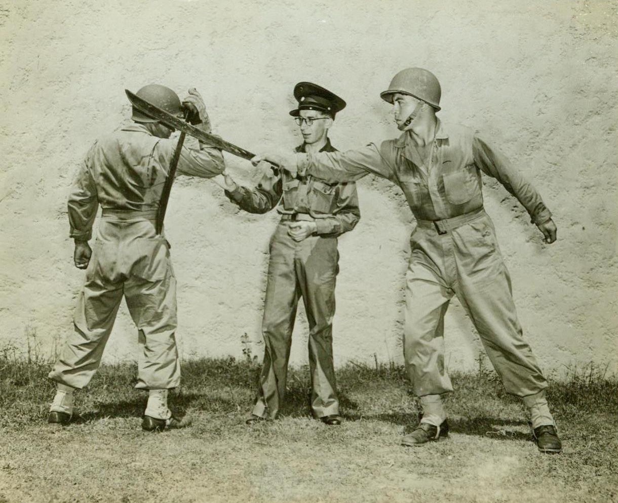 U.S. SOLDIERS LEARN JUNGLE FIGHTING, 8/5/1942. In this photo released by the U.S. Army Signal Corps, a Panamanian officer (center) instructs two American soldiers in the correct method of parrying a slashing stroke of a machete. This type of fighting is very important in jungle warfare. Credit: U.S. Army Signal Corps photo from ACME;