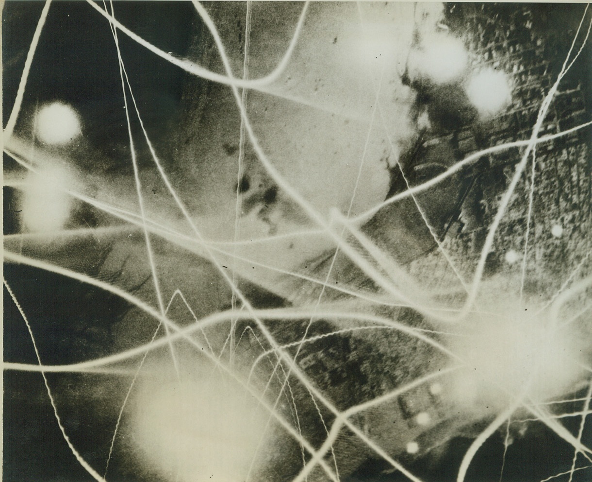 ALLIED BOMBERS ATTACK BENGHAZI BY NIGHT, 8/6/1942. This unusual photo, showing a criss-cross fire of tracer bullets, bomb flashes and brilliant white flashes of exploding anti-aircraft shells, was taken from a United Nations bomber during a night attack on the port of Benghazi. (Passed by censors.) Credit: ACME;