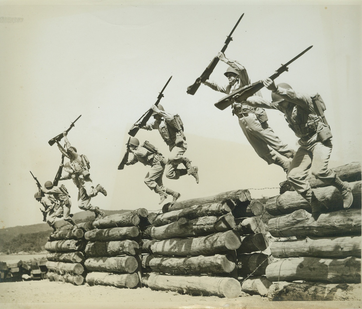 NOT FOR “SISSIES”, 8/6/1942. WEST POINT, NY – It takes a good, hard “Hunk O’ Man” to hurdle a barbed wire tangled log fence like this. But, these plebes take it in their stride as part of a 200 yard “assault” course, which includes everything from hurdling trenches, to taking a stab at dummies, which pop out at them unexpectedly. It’s part of the Army’s method of turning out officers that can meet – and conquer any emergency that may confront them on the battlefield. Course, is the toughest, shin-barking, back-breaking routine that can be cooked up, and these boys cover it in little more than four action-packed minutes. Credit: OWI Radiophoto from ACME;