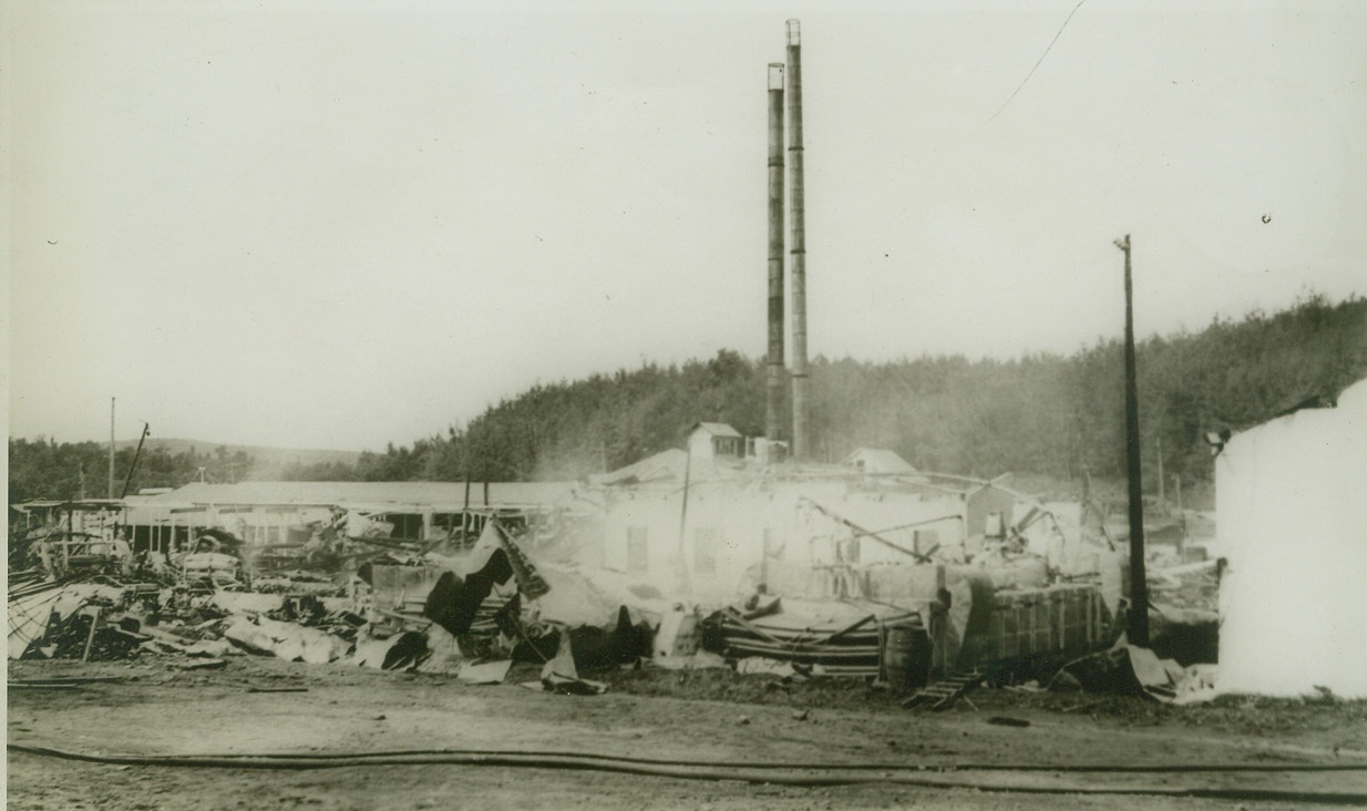 WORLD’S LARGEST AIRPLANE WOOD VENEER PLANT BURNS, 8/7/1942. CHICAGO, ILL. – The embers and twisted steel of valuable machinery after fire broke out in what was once the world’s largest airplane wood veneer plant at Mellen, Wisc., owned by the Penoke Veneer Company. The blaze apparently started by a short circuit and damage is estimated at $500,000. Credit: ACME;