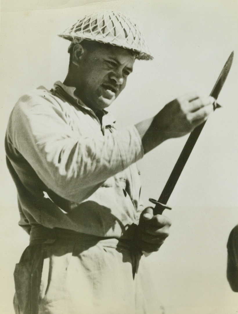 READY FOR THE NEXT!, 8/7/1942. EGYPT – A Maori soldier of the New Zealand forces in Egypt wipes his bayonet after a bloody engagement with Axis forces near El Alamein. The Maori favors such hand-to-hand fighting and looks on the bayonet as his best friend. The net over his helmet is to hold camouflage material. (Photo was released by New Zealand legation.) Credit: ACME;