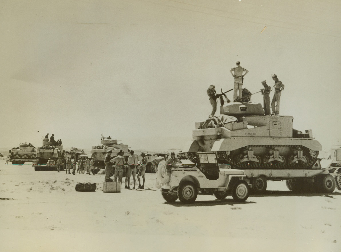 Desert Tank Taxi, 9/11/1942. Egypt—U.S. M-3 (General Grant) tanks, along with their American crews, are loaded onto trucks to be hauled closer to the actual fighting front on the Egyptian desert, where they will be unloaded to continue on their own. The tank-taxi service, a new wrinkle in desert warfare, saves wear and tear on both tanks and men. Passed by censors. Credit: ACME.;