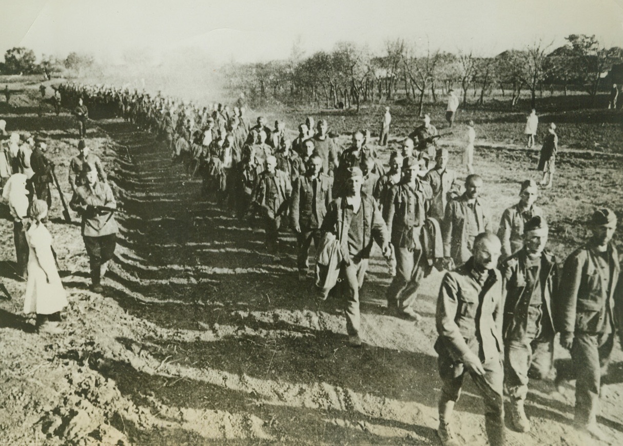 End of Their Army Careers, 9/17/1942. Russia—Russian villagers watch this long line of captured Nazi soldiers marching along a dusty road behind the Soviet lines into captivity. Their armed guards watch them closely. The Nazis are gaining ground in Russia, but only at the cost of many men lost and captured, and much equipment destroyed—if they can gain enough ground, they’ll lose the war. (Passed by censor). Credit: ACME.;