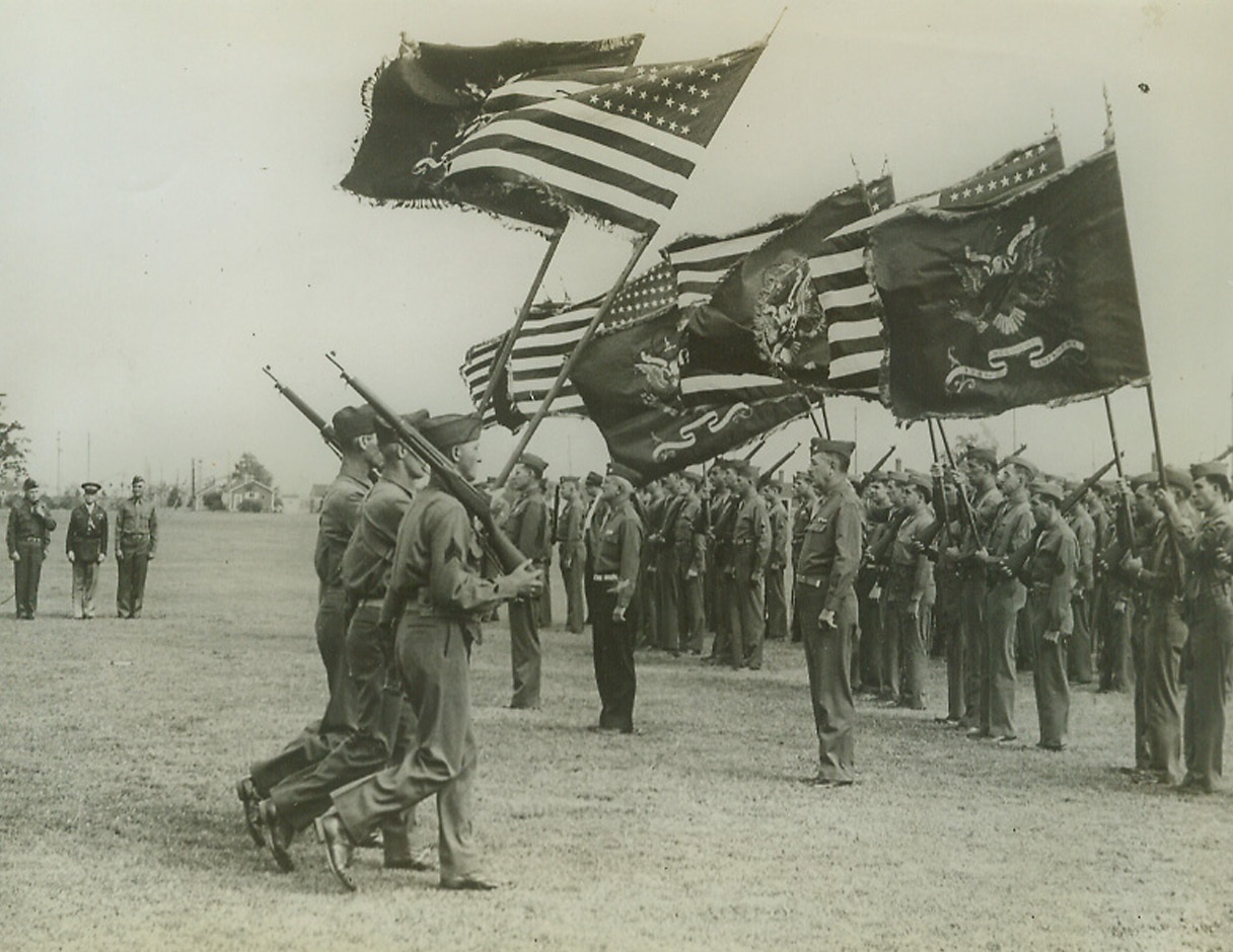 The New 94th Division Receives its Colors, 9/16/1942. Fort Custer, Mich.: Color guards are shown marching with Regimental colors and standards which were presented to the Regimental commanders of the new 94th division which was “activated” in formal divisional review. Major General Harry J. Maloney, Division Commander; Col. Young, and Brig. Gen. Louis J. Fortier, are shown at left.Credit: ACME.;