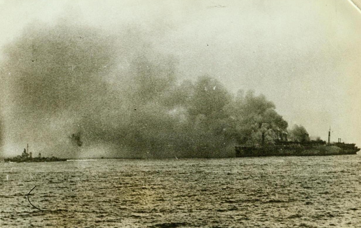 U.S. Transport Wakefield Afire At Sea, 9/9/1942. Washington, D.C. -- Smoke is blown to the Lee side of the U.S. Transport Wakefield as fire swept the vessel, Sept. 3, while it was returning to its home port with a convoy. At left is a destroyer, one of many ships that participated in the rescue of some 1600 passengers and crew members. The Wakefield, formerly the luxury liner S.S. Manhattan, has been salvaged and is now in an Atlantic port. 9/9/42 (ACME);