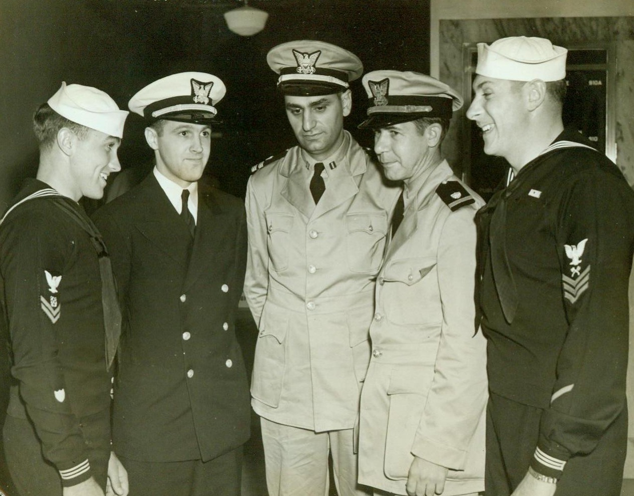 Saved From Burning Naval Transport, 9/9/1942. East Coast Port: -- These Coast Guardsmen were among the approximately 1,600 passengers and crew members aboard the 24,209-ton Naval Transport Wakefield, formerly the liner Manhattan, who were rescued when the vessel caught fire at sea the evening of Sept. 3. The ship has now been salvaged and towed to an American Atlantic port. Left to right: Boatswain's Mate (2nd Class) D.R. Fraser, of Buffalo, N.Y.; Lieut. H.P. Kniskern, Jr., New York City; Lieut. J. Mazzotta, Senior Deck Officer, of Cape May, N.J.; Ensign J.A. Mahrley, St. Paul, Minn., And Carpenter's Mate (1st Class) C. A. Buchert, Glenside, Pa. 9/9/42 (ACME);