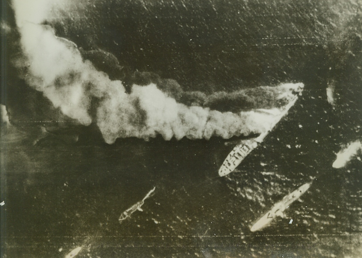 KEEPING SUPPLIES FROM ROMMEL, 9/17/1942. SOMEWHERE IN THE MEDITERRANEAN—Towering plumes of smoke drift back from a derelict Axis supply vessel which was hit amidships and in bows by an RAF bomber. This vessel of medium size was carrying supplies to Rommel’s hard-pressed army when it was intercepted, and received two direct hits. The British are waging an [sic] relentless bombing effort to keep the supply route to Rommel closed. Credit: Acme;