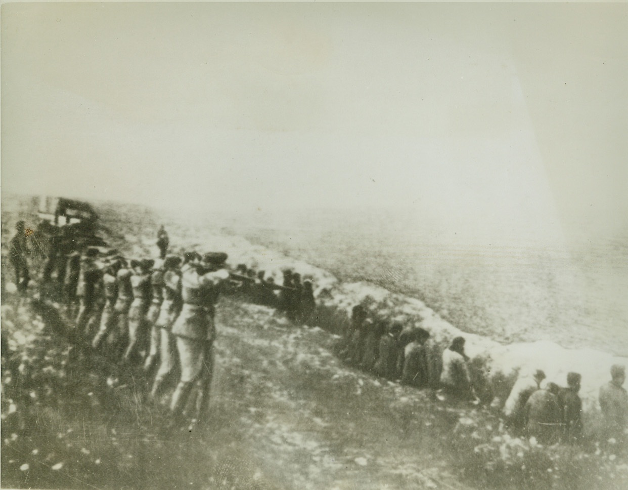 Nazis Execute Soviet Civilians, 9/27/1942. Russia – A German soldier proudly carried this picture. A long line of captured Soviet civilians sit beside their own mass grave, awaiting execution from the Nazi firing squad. The photo was taken from the body of a Nazi officer. Credit: (ACME);