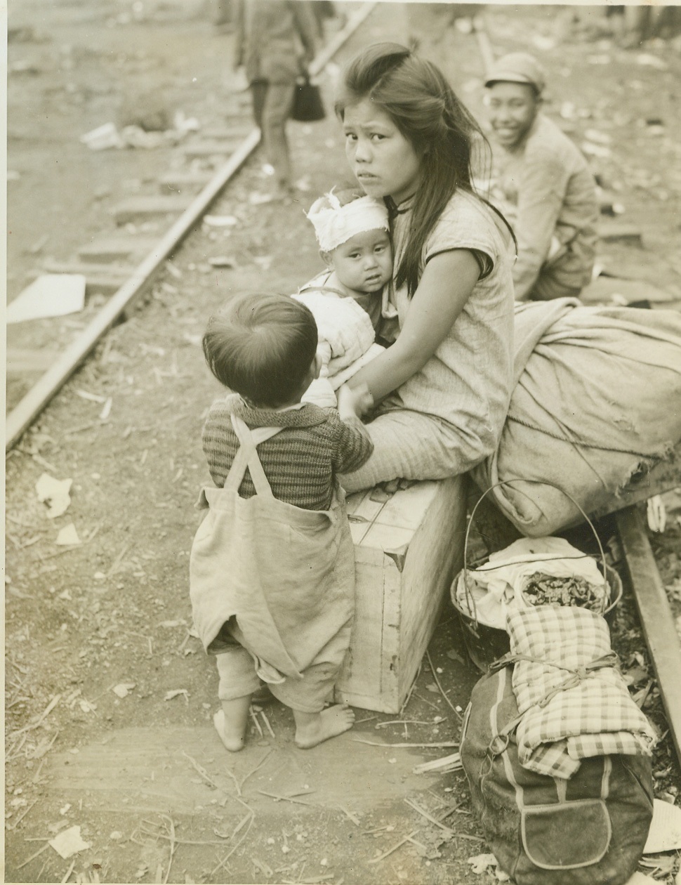 China’s Human Cargo, 11/10/1944. Eastern Front, China – Masses of humanity, united in one common purpose—flight for life—cram the railroads and highways leading from China’s Eastern Front, as the instinct for self-preservation sends them fleeing from Jap terror. Simple peasants they are, familiar with only the ways of simple folk like themselves, but they well know the atrocities of the Japs. Rather than live under the yoke of the Rising Sun, they choose to suffer hardship, and even death, to evade them. Trains leaving Liuchow are packed from the rails to the tops of the cars, and all available vehicles fill the highways as shown in this unusual and dramatic series of photos made by Frank Cancellare, ACME photographer for the War Picture Pool. On the heels of the evacuees follow constantly the fear of the dread typhus and cholera epidemics, but still they go onward. New York Bureau These refugees who were trying to escape on foot, pause by the railroad track to rest for a while. They hold the slim hope that a train may pass on which they can secure a little room. The young child has his head bandaged. Medical authorities along the way care for the refugees. Photo by ACME photographer, Frank Cancellare, for the War Picture Pool. Credit –WP-(ACME);