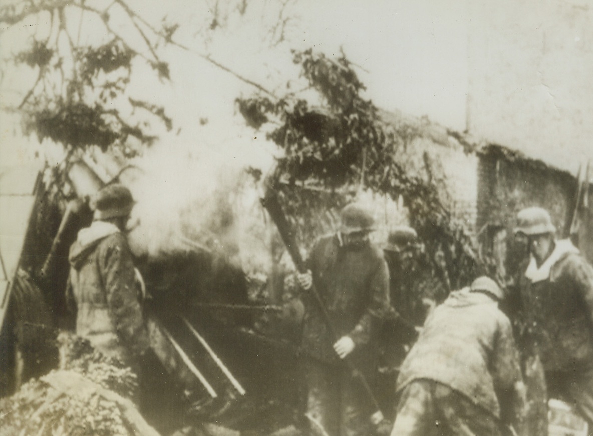 Firing Over Ruined Home, 11/23/1944. WUERSELEN, GERMANY—A camouflaged field howitzer fires over the ruins of houses in Wuerselen, according to the German caption accompanying this photo, which was radioed to New York from Stockholm. Credit: ACME RADIOPHOTO.;