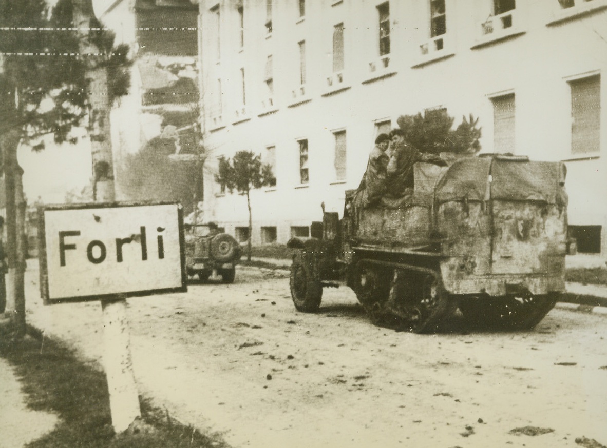 FORLI CLEARED BY 8TH ARMY, 11/10/1944. ITALY—British troops of the 8th Army have completed the conquest of Forli, heart of Italy’s wheat belt, and leading elements have passed through the town and reached the blasted bridge over the Montone River at the extreme western boundary. British tanks and troops are shown passing through the town.  Credit (OWI Radiophoto from ACME);