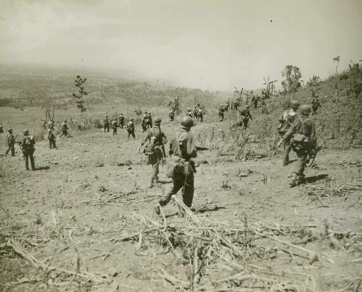Stalking the Jap, 11/13/1944. Leyte, Philippines – Hurrying across the stubble-strewn wasteland of Leyte island, infantrymen of the U.S. 96th Div. advance across Catamon Hill to hunt the Jap in his own territory.  Photo by Stanley Troutman, ACME photographer for the War Picture Pool.Credit Line-WP-(ACME);