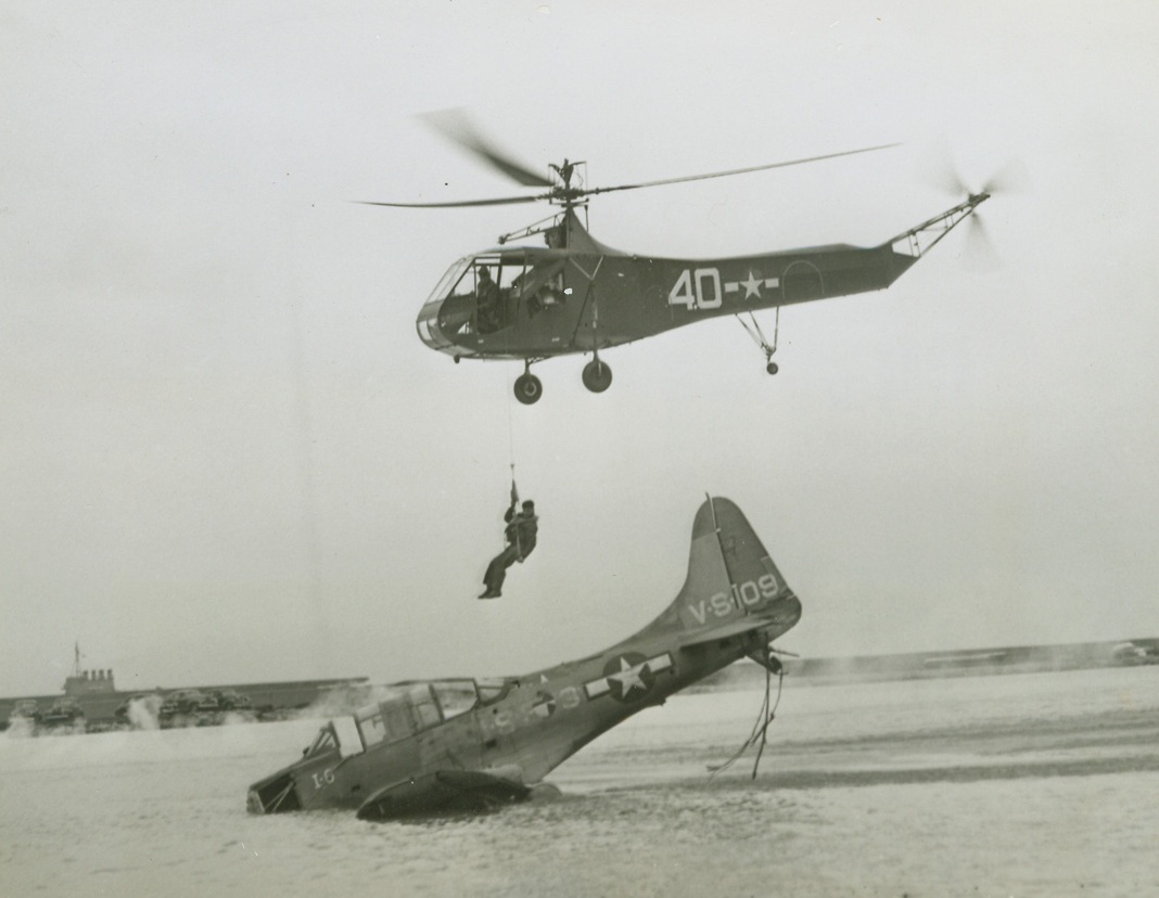 Lift to Life, 11/17/1944. Chicago—Michael Mastrone is lifted from simulated wreckage of a plane by a hydraulic hoist in a rescue demonstration which is part of the Navy Bond show being staged in Chicago. The Coast Guard helicopter is piloted by Lt. (j.g.) W.C. Bolton.Credit: ACME.;