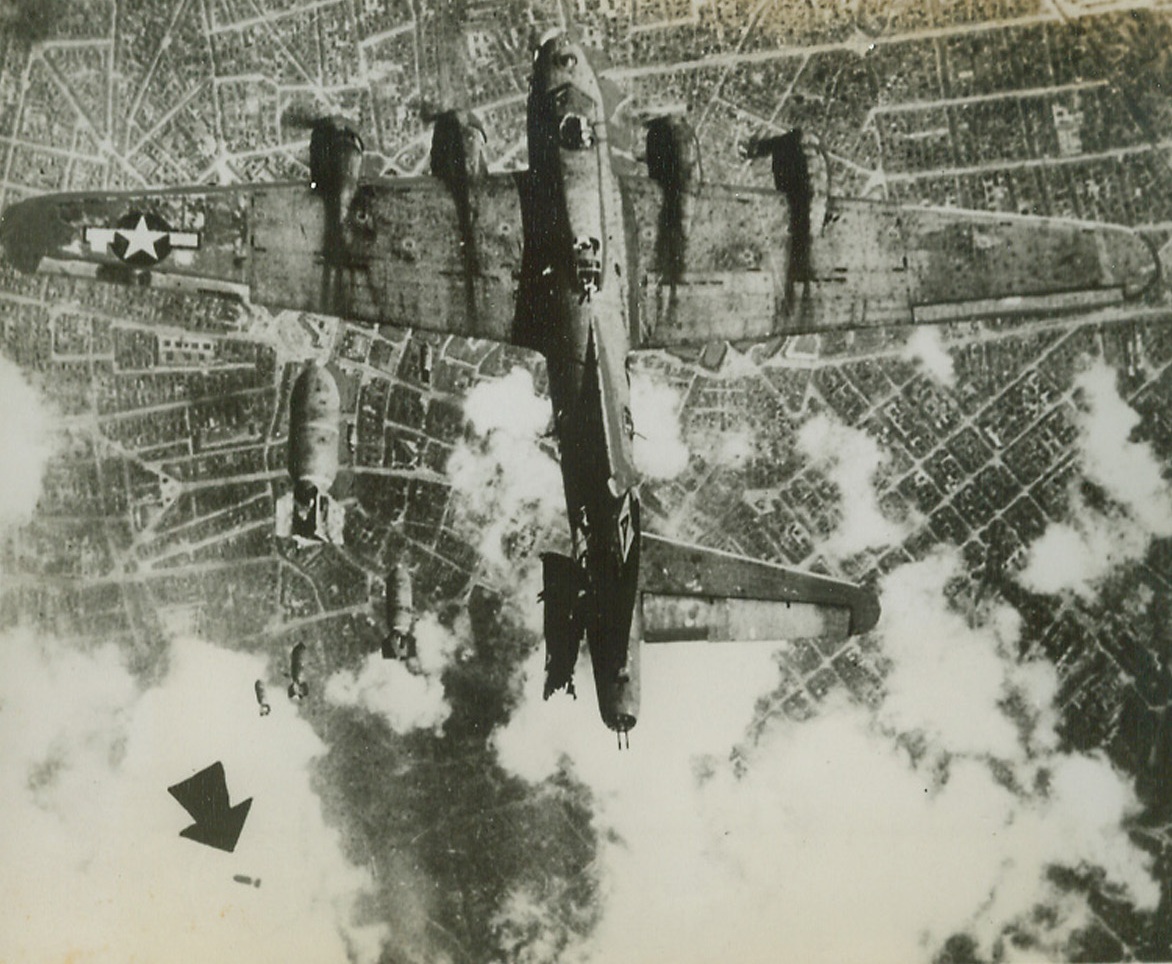 Completes Mission Despite Mishap, 11/3/1944. Seattle, Wash: Boeing Aircraft Co. of Seattle, has released this picture of a B-17 bomber over unidentified European city. The plane in close flight formation while laying precision pattern of explosives on target, has left stabilizer sheered off by bomb released from plane directly above. Bomb that struck plane veers away from target (arrow). Mishap did not prove fatal as mission was completed and ship arrived safely at home base.Credit: ACME.;