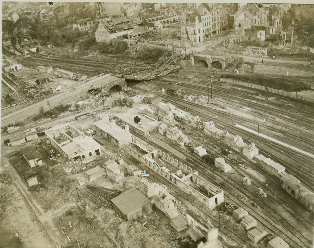 Allied Bombs Smashed Aachen Rails, 11/3/1944. GERMANY -- This striking aerial photo, taken after the fall of Aachen, shows the devastating effect of Allied bombing in the area near the railway station and marshalling yards of the key German city. The road bridge over the railway has been demolished by direct hits. Warehouses, rolling-stock and supplies in the sidings have been wrecked by accurately aimed bombs. Photo by Acme photographer, Andrew Lopez, for the War Picture Pool. Credit-WP-ACME;
