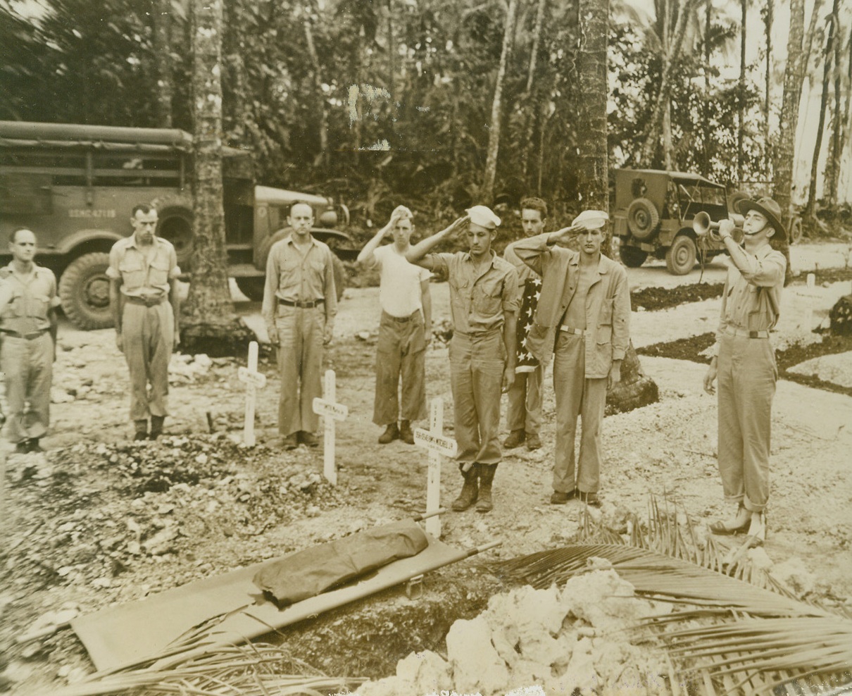 Taps Fro Good, 1/18/1944. SOLOMONS—While Taps sound for him the last time, a group of fighting men pay their respects to a fallen buddy somewhere in the Solomons.   A stretcher lies over his grave and on the faces of the saluting men is written the realization that there will be no road back for him.Credit:  Official US NAVY Photo from ACME;