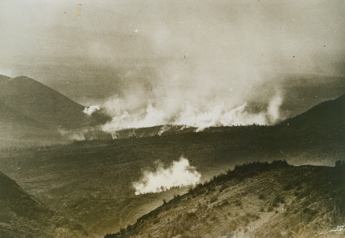 WAR-FILLED VALLEY, 1/22/1944. ITALY—German and Allied shellbursts fill the Ori Valley with smoke and deafening sound, as the Fifth Army battles toward Cassino. American dive-bombers added their explosives, at intervals, as we fought to wrest the territory from the Nazis. Credit: Acme;