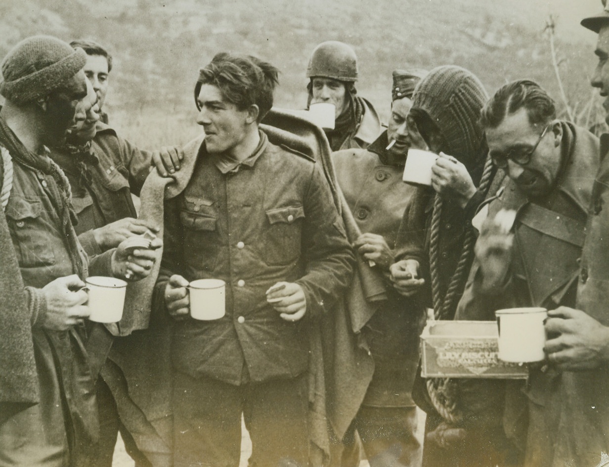 DRESS RHEARSAL FOR “ROME” INVASION, 1/22/1944. ITALY—After a surprise amphibious assault on German positions in Italy, black-faced Commandos share tea and biscuits with a German prisoner they brought back from the raid which was probably a test-rehearsal for the new Allied invasion behind enemy lines below Rome. British Commandos, Rangers, and Fifth Army troops are taking part in the present major assault to break enemy winter lines. Credit: Acme;