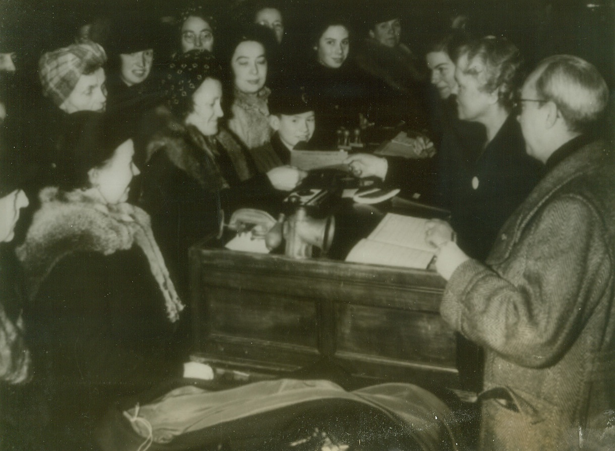 BERLIN HOUSEWIVES DO THEIR MORNING BARTERING, 1/22/1944. BERLIN—Striving to look cheerful for the photographer, Berlin housewives obtain estimates on the value of the articles they wish to barter, at one of the German capital’s 23 “exchange” centers. A meat grinder, coat, and shoes are seen among the possessions these bombed-out women wish to trade for articles they lack. The Nazis established the system to help out Berliners who have lost virtually everything from Allied bombings. (Photo radioed from neutral source.) Credit: Acme radiophoto;