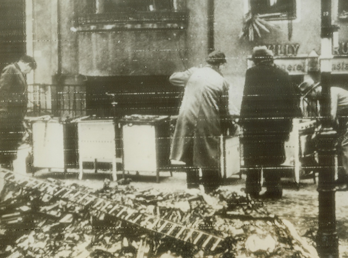 Scavenger Hunt, 1/19/1944. BERLIN—Residents of Berlin are trying to salvage everything possible from the bombed ruins of the German capital. According to German caption accompanying this photo, radioed from Stockholm this morning, the salvagers concentrate on doors, windows, iron beams, bathtubs, washtubs, furnaces and stoves which can be used in repairable houses or as scrap. Here a group of Berliners are looking over a batch of salvaged stoves. Credit: ACME RADIOPHOTO.;