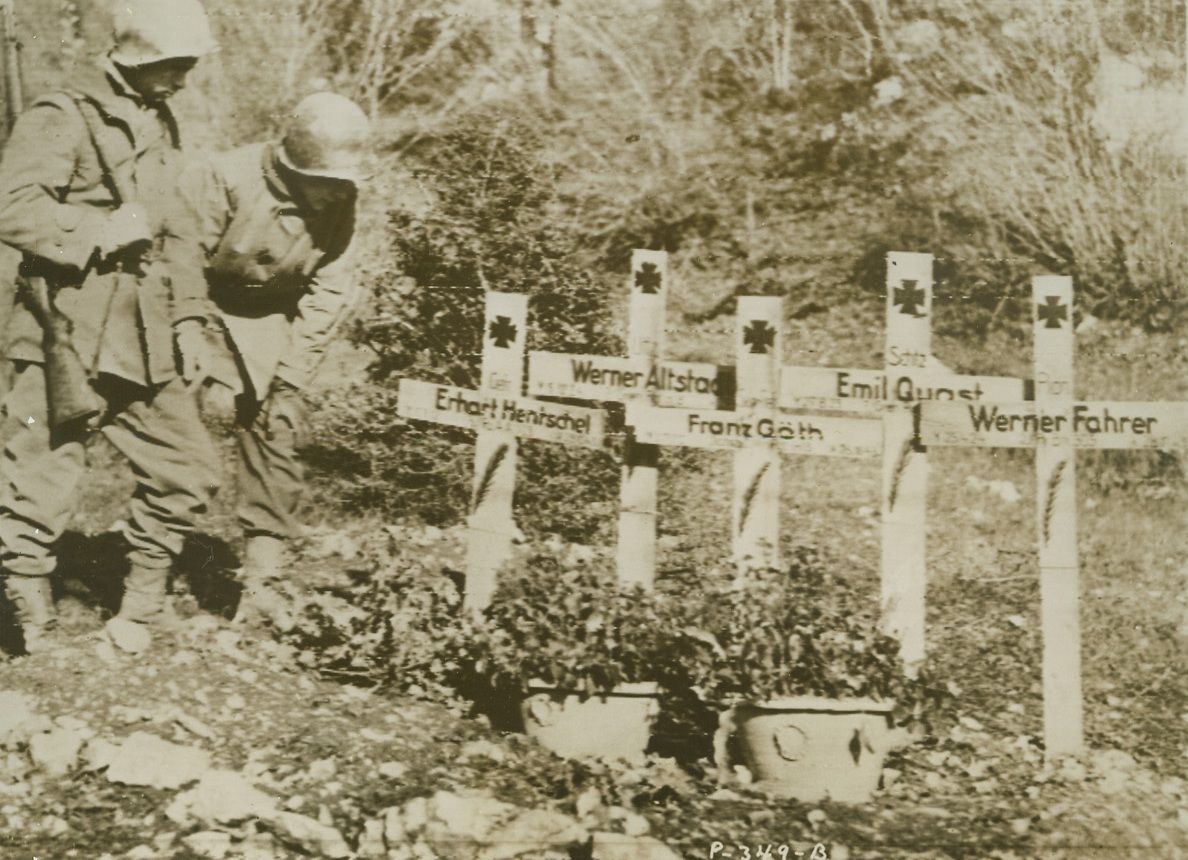 Five Graves on Rome Road, 1/5/1944. VANAFRO, ITALY—Crowded together, five crosses mark the final resting place of Nazi warriors who died on the road to Rome, in an attempt to stem the Allied advance on Venafro. Two American soldiers stop to inspect the graves. Left to right: Pvt. Reno F. Fiate of Bristol, Conn.; and M/Sgt. Robert Heller of New York City. Credit: U.S. SIGNAL CORPS RADIOTELEPHOTO-ACME.;