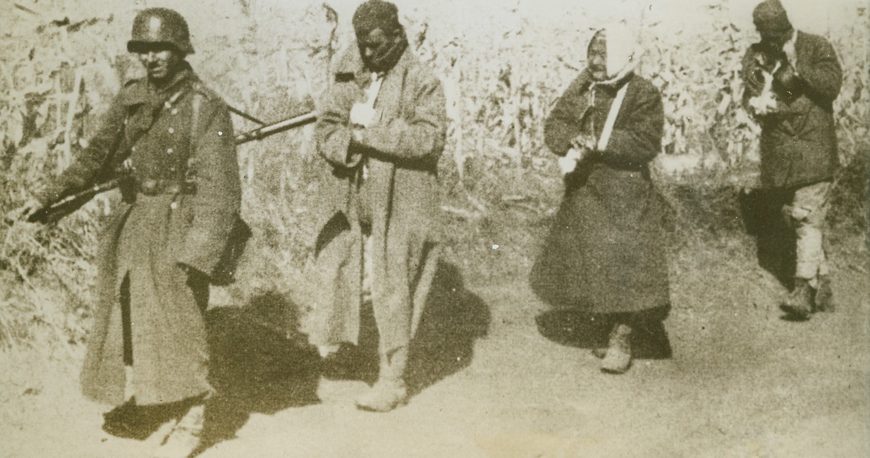 Prisoners of the Germans, 1/16/1944. SOMEWHERE IN RUSSIA – Two Soviet partisans, and one old woman rounded up with them, trudge wearily behind their Nazi captor, who takes them to headquarters for “questioning”. All badly wounded during fighting as the rear of German lines, the prisoners know that they can expect no mercy from Hitler’s men, who wince at the mere mention of Soviet guerillas. Photo obtained through a neutral source.Credit Line (ACME);