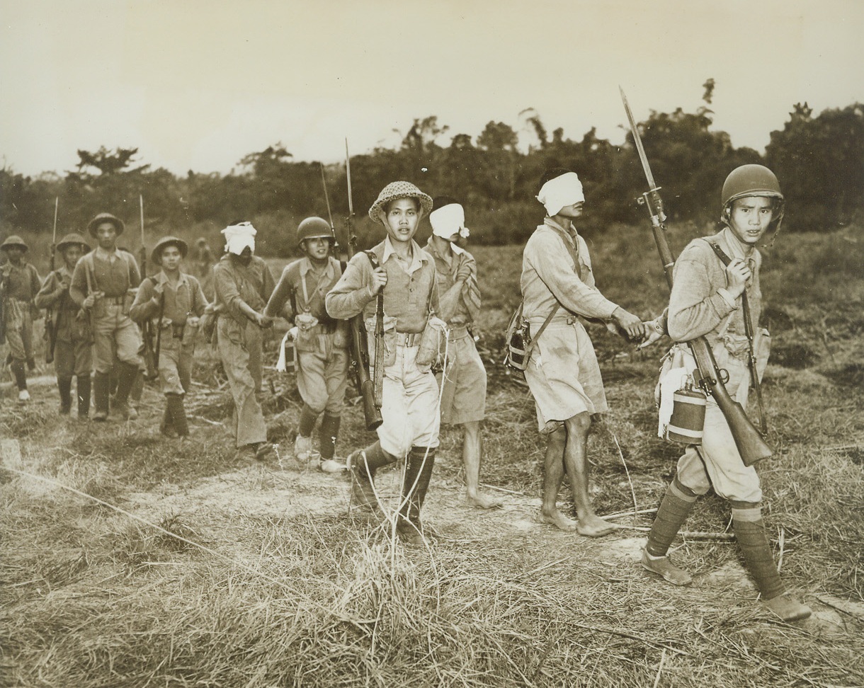 Nips Captured by Chinese in Burma, 1/31/1944. Burma – Three blindfolded Japanese are led to the rear by Chinese soldiers after their capture on the front in Northern Burma, where American trained and American equipped Chinese troops are fighting the Japs. Note modern U.S. combat helmets on soldiers (at right and fifth from right). (Passed by censors.) Credit: ACME photo by Frank Cancellare for the War Picture Pool;