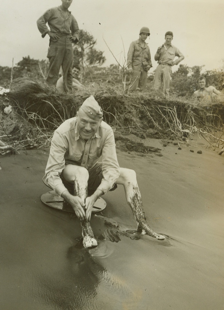 General Cools his Dawgs, 1/18/1944. New Britain – Major General W.H. Rupertus has a sure-fire cure for aching feet.  After a hard day of tramping about the New Britain front with his troops, he treats his barking dawgs to a cool sea water bath – getting rid of the mud he collected on his tour.Credit Line –WP—(ACME photo by Frank Prist, Jr for the War Picture Pool);