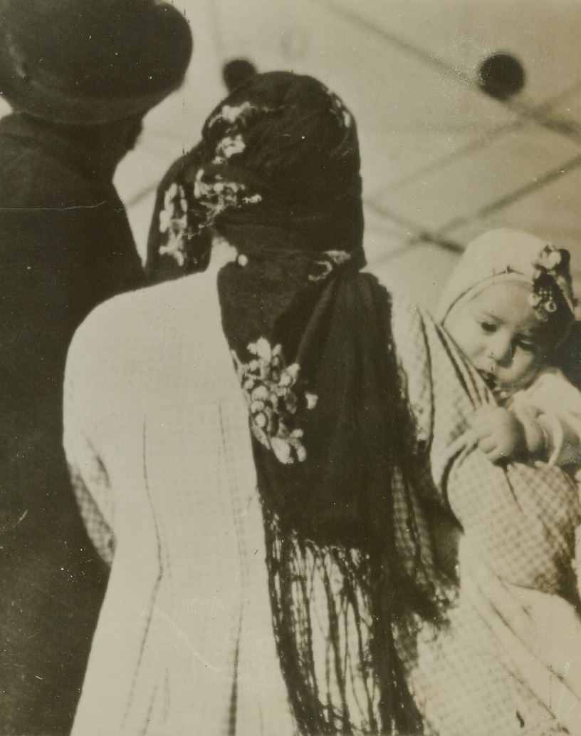 Heading for a New Homeland, 1/10/1944. A North African Port—A refugee family, left homeless by Hitler’s ruthless advance in Europe, wait to board a ship at a North African port, which will take them to Palestine. There they will be given a chance to establish themselves as agricultural settlers. Credit: OWI radiophoto from ACME.;