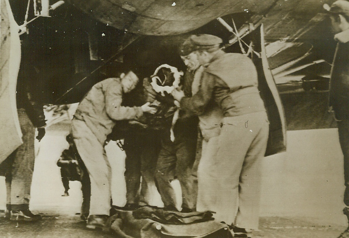 Wounded Waist Gunner Returns to Base, 1/31/1944. Washington, D.C.: Wounded when a 20mm shell exploded near his post, the waist gunner of a Flying Fortress is shown being removed through the bomb bay doors. The ship was on a mission to Frankfort in which some 800 bombers participated. Credit: US Army Signal Corps Radiotelephoto from ACME.;