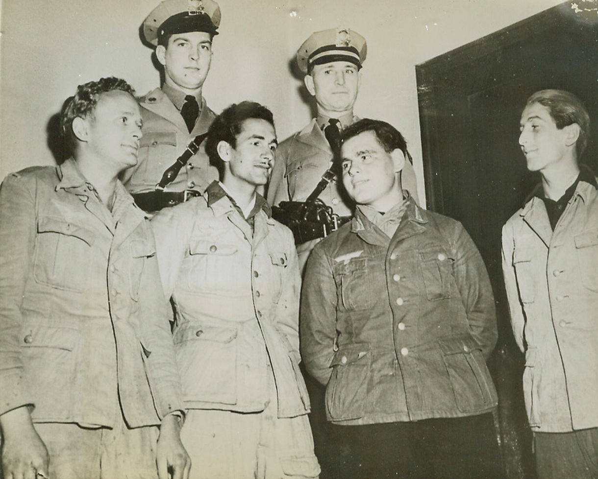 Nazis Recaptured After Escape, 1/9/1944. Wichita, Kans.—Four Nazi war prisoners caught near Wichita, Kansas, seem unruffled after being taken in the biggest manhunt of the region’s history by state highway patrolmen Capt. Paul Drescher (near right) and Galen Bennett (left). The prisoners (left to right) Hans Hass, 22; Alfons Putliewitz, 19; Enno Heyer, 20; and Karl Schroader, 25, escaped from a train near Elndale, Kansas. Credit: ACME.;