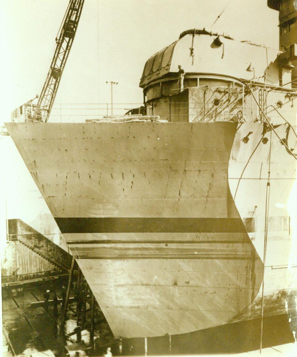 Stubby bow brings her home, 1/12/1944. BREMERTON, WASH. – With stubby temporary bow, this torpedoed U.S. cruiser made her way home from southwest Pacific battle area. A new bow was begun at Puget Sound Navy Yard, Bremerton, Wash., while the cruiser was enroute from south Pacific, and upon arrival she was quickly repaired and sent back into battle, a more deadly fighter than before. CREDIT LINE (U.S. Navy photo from ACME) 1/12/44;