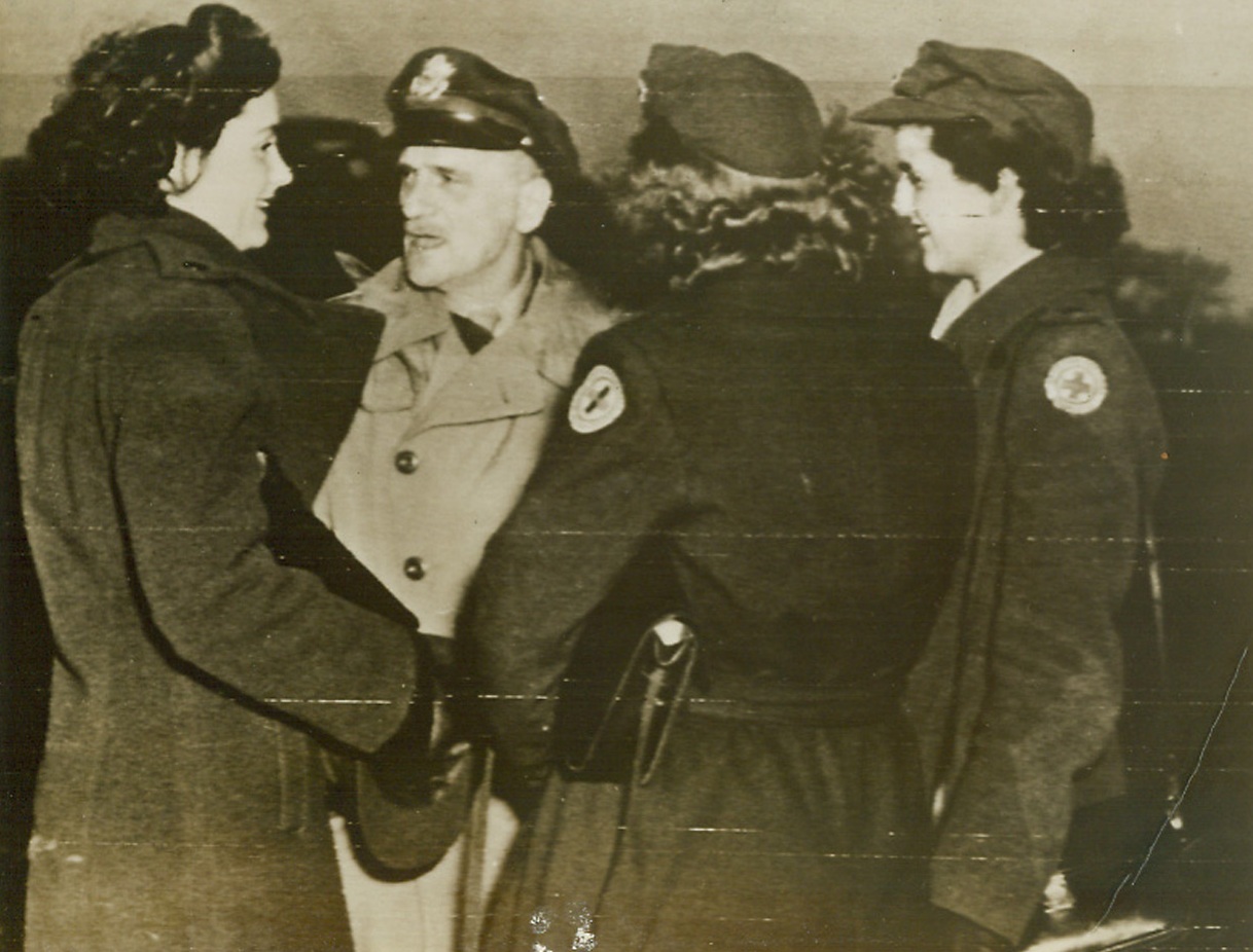 DAD GREETS HIS DAUGHTER, 1/5/1944. SOMEWHERE IN ENGLAND—Arriving at a Fortress base somewhere in England, Red Cross worker Tatty Spaatz (left) is greeted by her distinguished dad, Lt. General Carl Spaatz, American commander of strategic bombing in the invasions of Western Europe. With back to camera is Dorothy Mairek of Fort Wayne, Ind., and (at right) Virginia Sherwood of New York City, both Red Cross workers. Credit (Signal Corps Radiotelephoto from ACME);