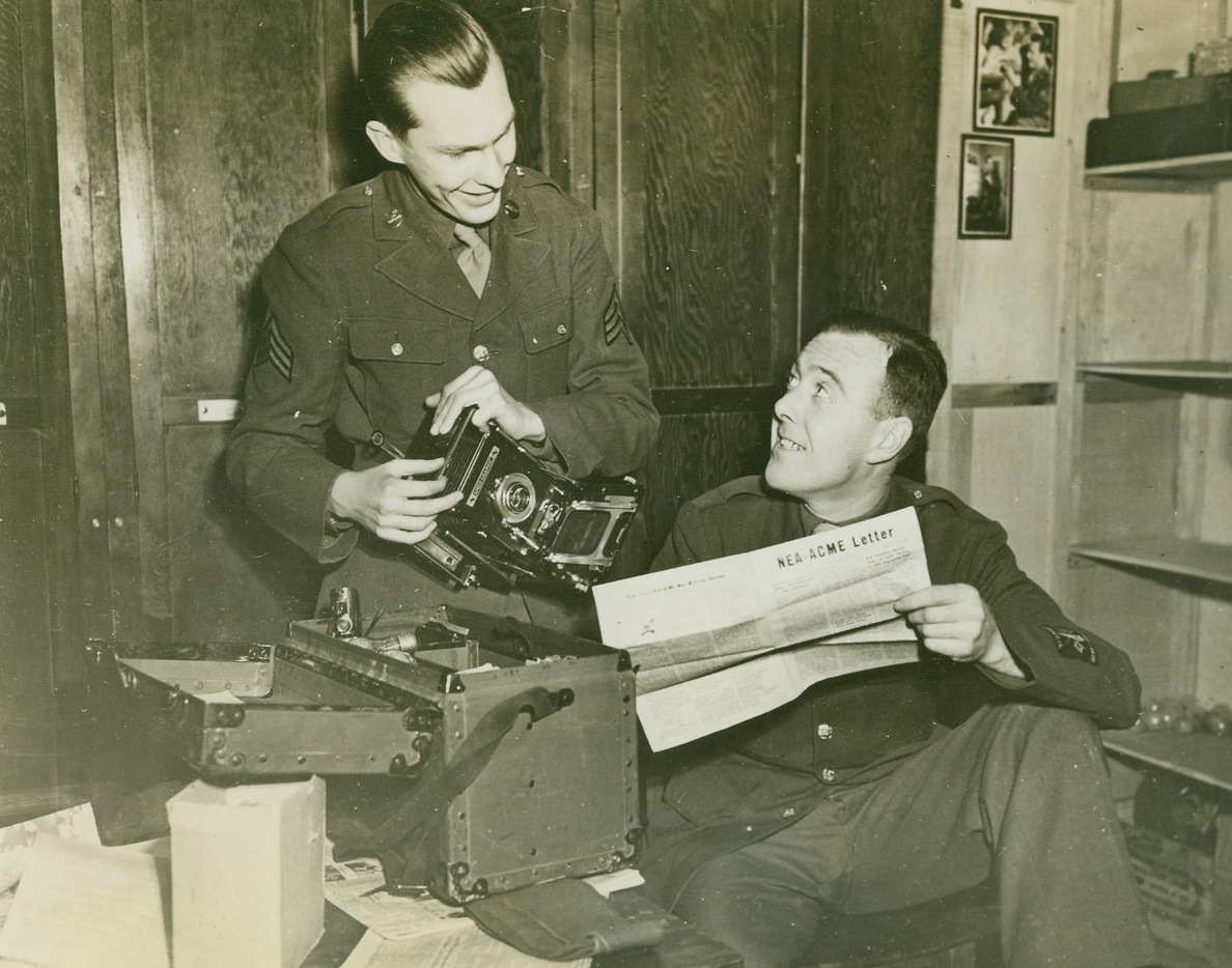 Hello Again, 1/7/1944. Somewhere in England – Meeting in England, a year and a half after both boys worked on ACME Newspictures’ photographic staff, Sgt. Reginald Kenny (left) of Somerville, New Jersey, and Sgt. Bruce Bacon, of Rockville Centre, Long Island, New York, catch up on their news of the boys back at the home office. Sgt. Bacon, who reads the NEA-ACME letter, is with the Army Pictorial Service. Sgt. Kenny is with the U.S. Army Public Relations Office. Credit: ACME;
