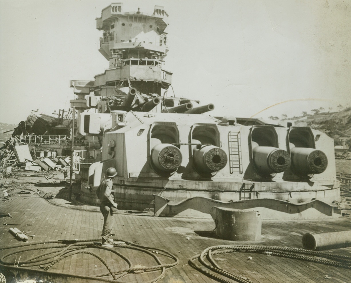 Scuttled “Strasbourg”, 10/7/1944. Toulon, France – A Yank surveys the remains of the scuttled French battleship “Strasbourg”, which lies beside oil docks in Toulon Harbor.  The long Snouts of four lower turret guns in the foreground have been cut off. Credit:  Signal Corp Photo From ACME;