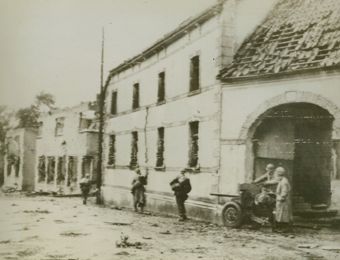 Nazi Hunt, 10/5/1944. While a crew of their buddies stands ready with an anti-tank gun, an American patrol advances slowly down the street in this German town, looking for Nazi sniper nests and traps. Credit: Army radiotelephoto from ACME.;