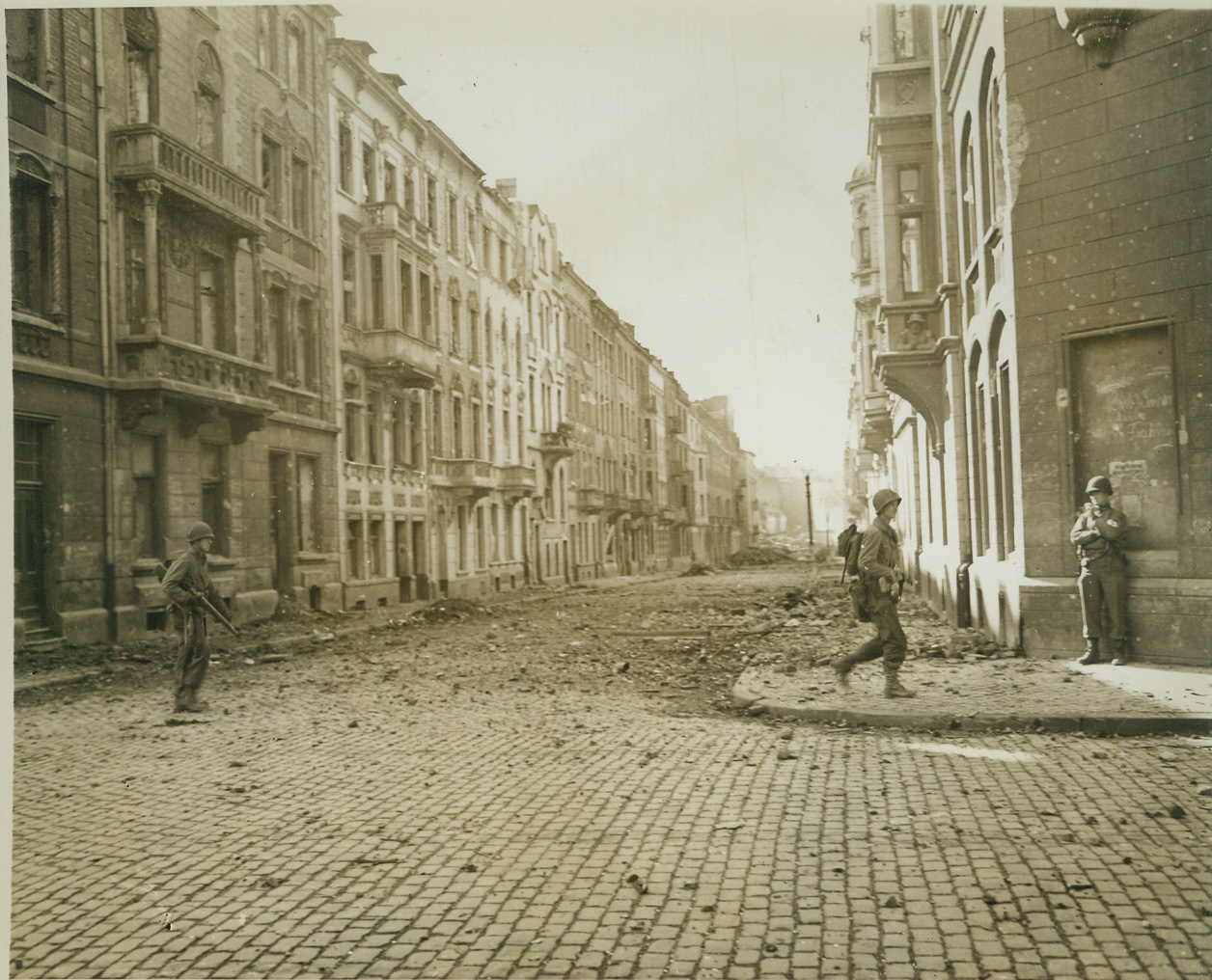 Yanks Fight in Aachen Streets, 10/19/1944. Germany – American soldiers stand in the rubble-littered streets of Aachen as fighting for this Nazi stronghold was brought into the city proper. Photo by ACME photographer, Andrew Lopez, for the War Picture Pool. Credit – WP – (ACME);
