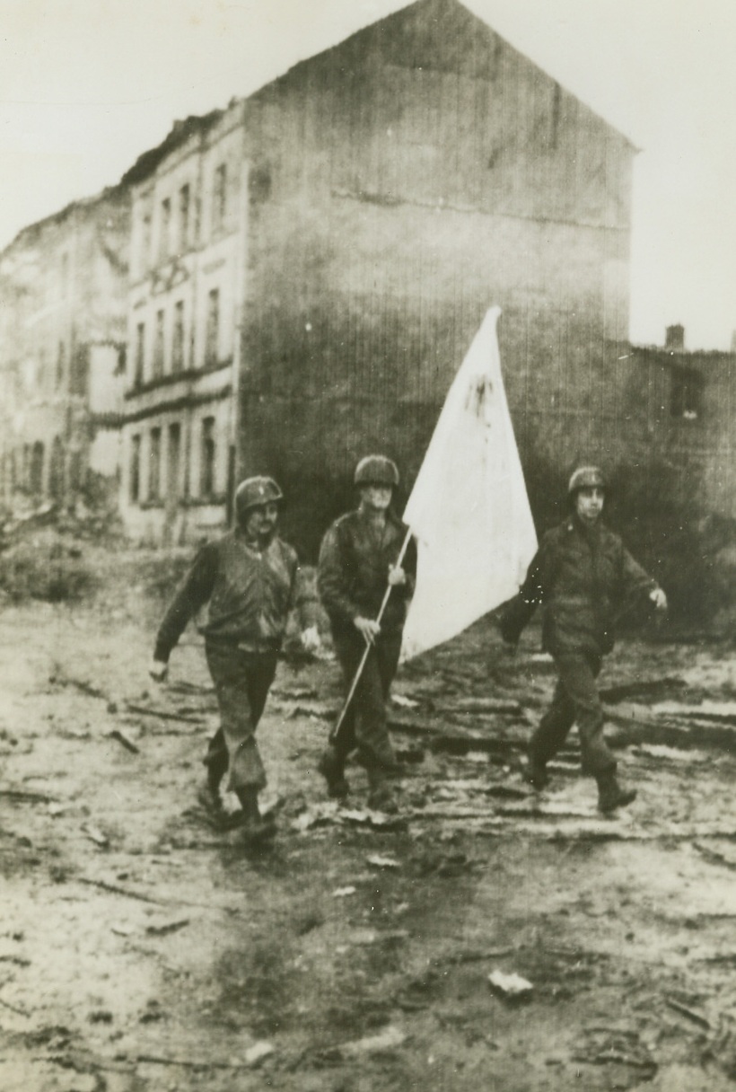 NGING ULTIMATUM TO AACHEN, 10/12/1944. Carrying terms demanding the unconditional surrender of the German forces in Aachen, are (left to right): Lt. William Boehme, of 66th Street, New York City; who served as interpreter; Pvt. Kenneth Kading, LaGrange, Ill., who bears the flag of truce made from a bedsheet; and Lt. Cedric Lafley, of Enosburg Falls, Vt., who commanded the party. Alternative to surrender was the “obliteration” of the city. Nazis refused to give up and the Allies are pounding Aachen to bits.Credit: Acme photo by Andrew Lopez for War Picture Pool;