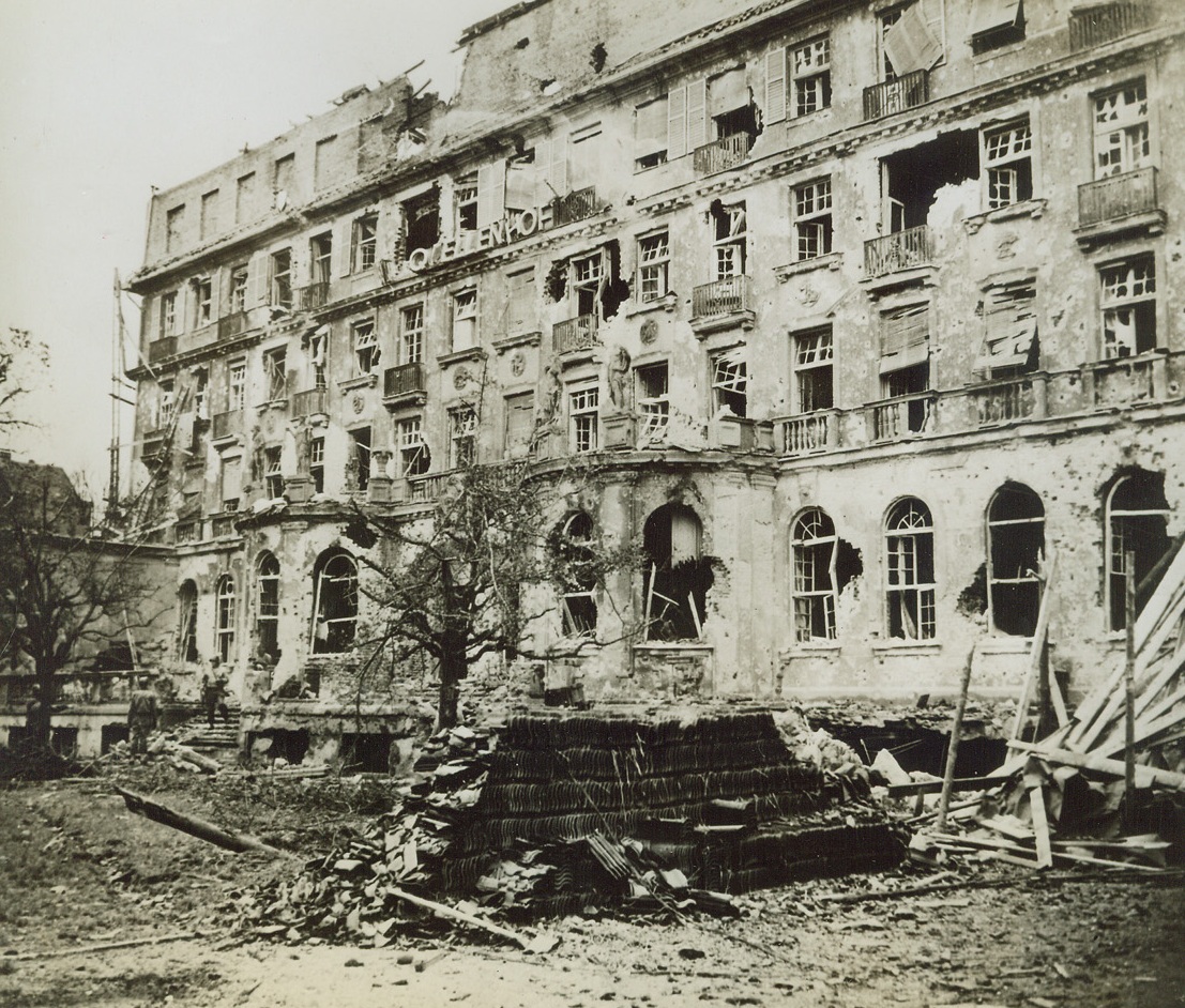NAZI HEADQUARTERS IN AACHEN, 10/28/1944. GERMANY—This is a view of the Palace Hotel in the Quellenhof which was used as headquarters by the Nazi defenders of Aachen. A group of American GI’s enter the battered building. Credit: Acme;