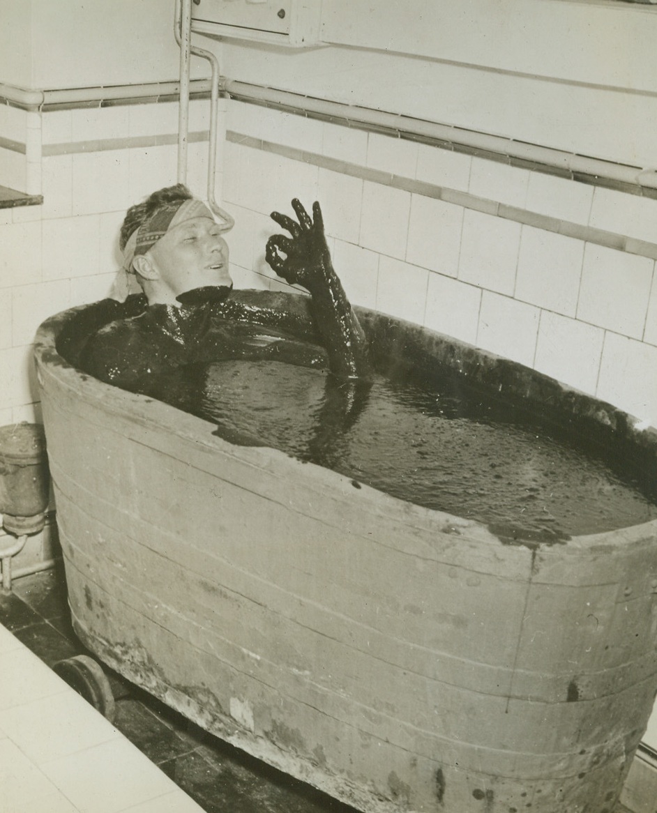HERE’S MUD IN YER TUB, 10/10/1944. SPA, BELGIUM—Any similarity between this slimy batter and the variety of mud found in a GI’s front line trench is purely coincidental. For one thing, Sgt Edward E. Shelton of San Antonio, Texas, chose to immerse himself in the oozing stuff. For another, it’s supposed to be healthful. It might look the same to this Yank, but after aiding in the liberation of the town of Spa, he decided that it would be shameful not to take advantage of the famous mineral and mud baths. Credit: Signal Corps photo from Acme;