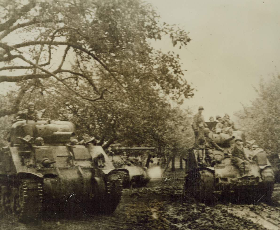 G. I. HITCH-HIKERS, 10/8/1944. UBACH, GERMANY—Moving up to the front near Ubach, these troops hitch a ride on board a medium tank. Credit: Army radiotelephoto from Acme;