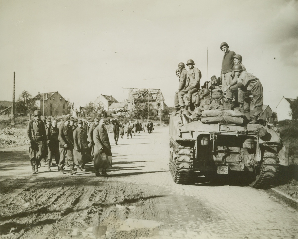 They Quit Aachen Battle, 10/18/1944. Guarded by an American Infantryman, a long line of Germans surrenders to the crew of a U.S. 1st Army tank in the battered city of Aachen, Germany. Credit: (ACME) (WP);